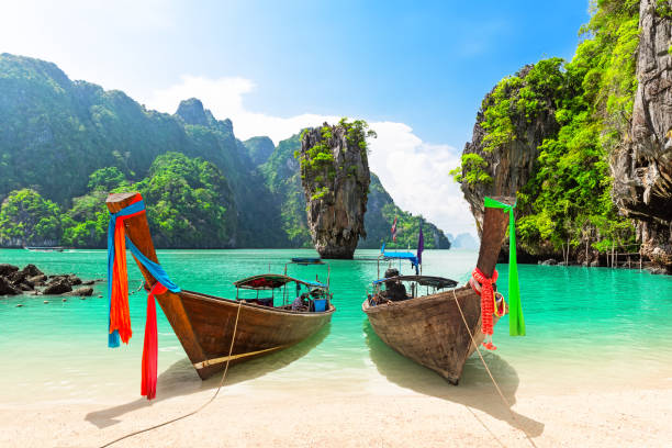 Famous James Bond island near Phuket in Thailand. Travel photo of James Bond island with thai traditional wooden longtail boat and beautiful sand beach in Phang Nga bay, Thailand.